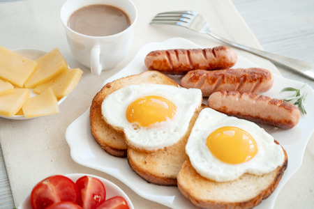 Breakfast with love - fried eggs in the shape of a heart, fried sausages and coffeeの写真素材
