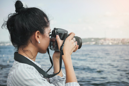 Woman photographer, taking pictures of landscape at seaの写真素材