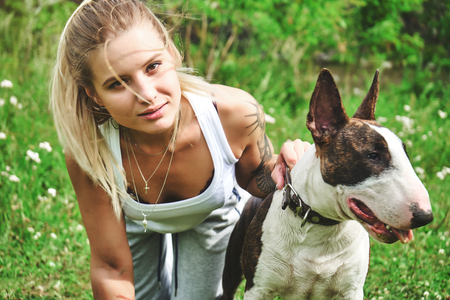 Girl on a green grass with bull terrierの写真素材