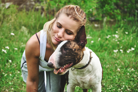 Girl on a green grass with bull terrierの写真素材