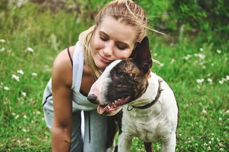 Girl on a green grass with bull terrierの写真素材