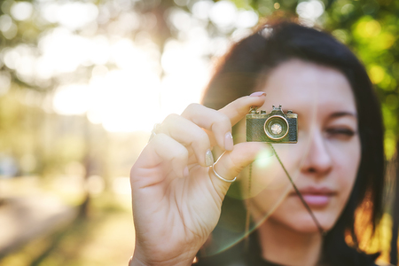 Woman photographer, taking pictures on her jewelry camera at sunsetの写真素材