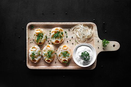 Home made chinese dumplings served on the cutting board with sour cream sauce, parsley, and onion. Top Viewの写真素材