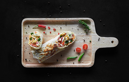 wrap sandwich fresh roll of lavash. Traditional Middle Eastern snack on cutting board on wooden backgroundの写真素材