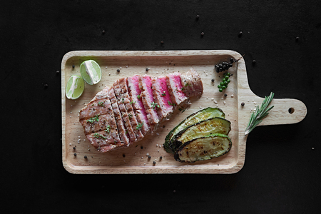 Grilled tuna steak with spices and vegetables on cutting board. Top viewの写真素材