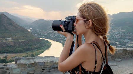 Female photographer, taking pictures of mountain landscape at sunsetの写真素材