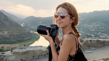 Female photographer, taking pictures of mountain landscape at sunsetの写真素材