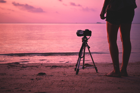 Woman photographer, taking pictures of landscape at sunsetの写真素材
