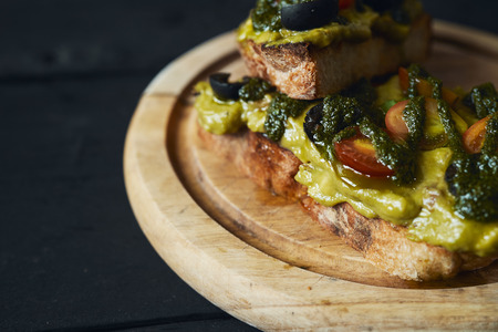 Fresh avocado toast with spices on wooden cut board on dark background, top viewの写真素材