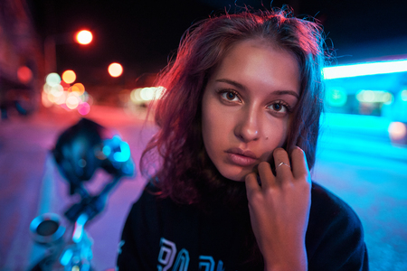 Neon close up portrait of young woman wear hoodie. night city street shotの写真素材