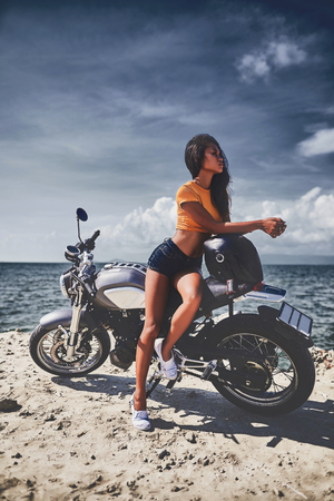sexy asian woman near her vintage custom motorcycleの写真素材