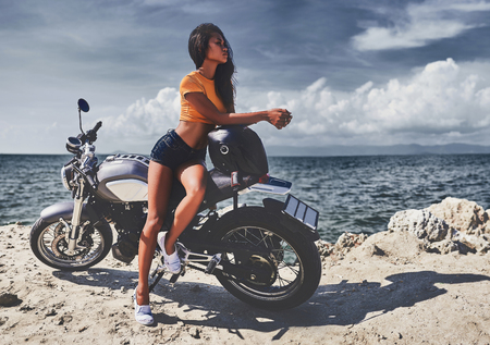 sexy asian woman near her vintage custom motorcycleの写真素材