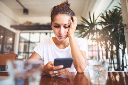 Portrait of beautiful girl using her mobile phone in cafe.の写真素材