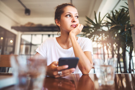 Portrait of beautiful girl using her mobile phone in cafe.の写真素材