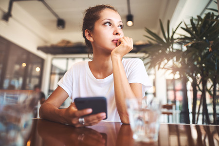 Portrait of beautiful girl using her mobile phone in cafe.の写真素材