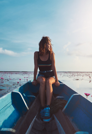 outdoors portrait of young woman is sitting on blue boat while tour on thale noi lakeの写真素材