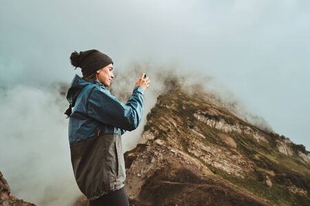 A hiker girl take a pictures on a smartphone on the mountainsの写真素材