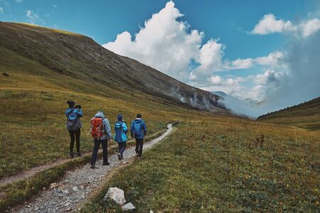 A group of hikers walking down a mountain trail, clouds in a gorge in the background. Bzerpinskiy Karnizの写真素材