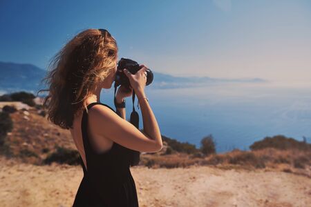 Beautiful woman professional photographer with dslr camera shooting landscape in sunset light in Turkeyの写真素材