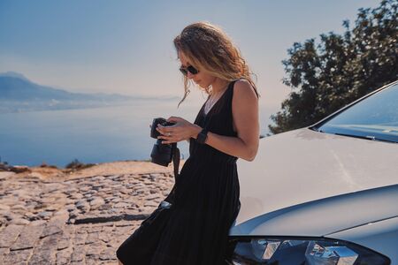 Beautiful woman professional photographer standing with dslr camera near her car while travel in Turkeyの写真素材