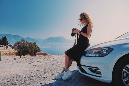 Beautiful woman professional photographer standing with dslr camera near her car while travel in Turkeyの写真素材