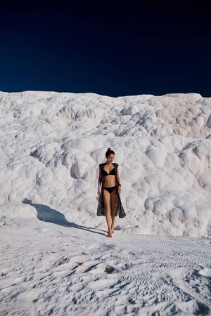 Young beautiful girl in black dress standing at natural pool Pamukkaleの写真素材
