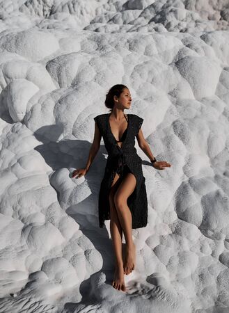 Young beautiful girl in black dress standing at natural pool Pamukkaleの写真素材
