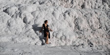 Young beautiful girl in black dress standing at natural pool Pamukkaleの写真素材