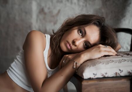Beautiful woman model put her head on a chair in hotel roomの写真素材