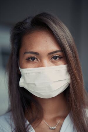 young beautiful Asian woman or hospital nurse using protective medical face mask in prevention vs virus infection.の写真素材