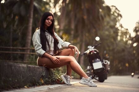 Sexy woman with a black motorcycle in cafe racer style