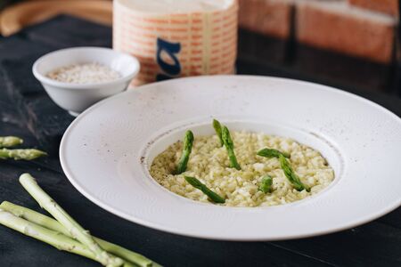 Risotto with asparagus in white plate on a black wooden table. View from above.の写真素材