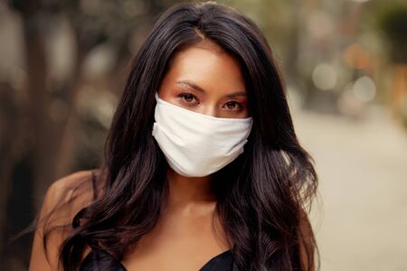 Beautiful Asian woman wearing surgical face mask protection against virus. Fashion Asian model with white medical maskの写真素材