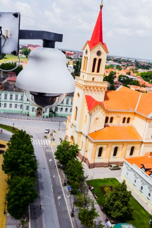 High tech overhead security camera at a tall building oversees City area の写真素材