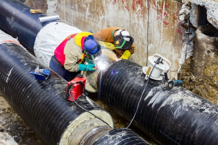 Welders with protective equipment welding outdoors pipeline construction.の写真素材