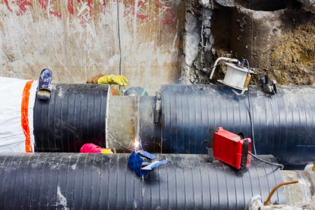 Welders with protective equipment welding outdoors pipeline construction.の写真素材