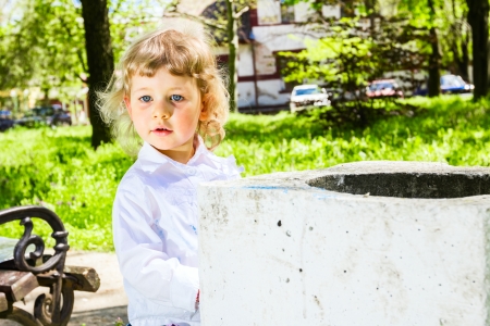 Child with dirty hands looking in too concrete trash canの写真素材