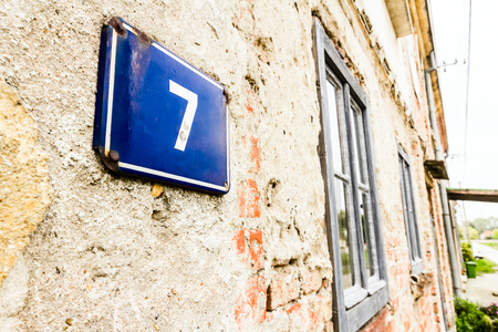 Blue aluminum house number 7 on a red brick wall