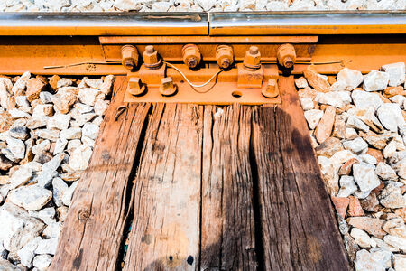 Close view of railroad track, old fashioned rusty clamps and screws wooden railroad.の写真素材