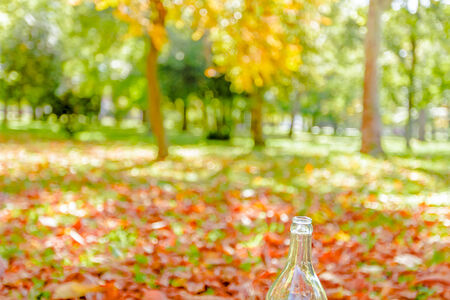 Empty transparent bottle on the autumn background, beautiful landscapeの写真素材