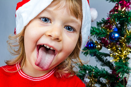 Portrait of a lovely little girl who is wearing Santa hat, she is standing against the Christmas background.の写真素材