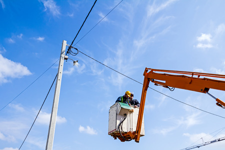 Technician works in a bucket high up on a power pole.の写真素材