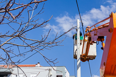 Technician works in a bucket high up on a power pole.