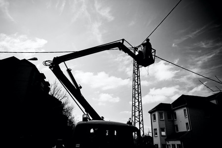Technician works in a bucket high up on a power poleの写真素材