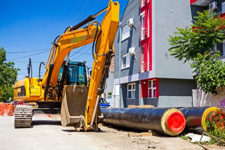 Excavator loader with backhoe is standing over blue sky in city street
