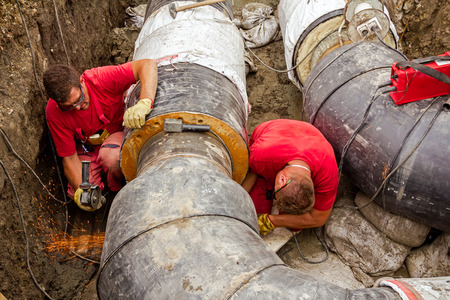 Metal workers are grinding first weld on new pipeline.