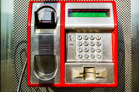 Red public telephone is attached on metallic background, phone and headset.の写真素材
