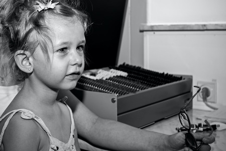 Little girl is at the eye examination showing directions of signs on board.の写真素材