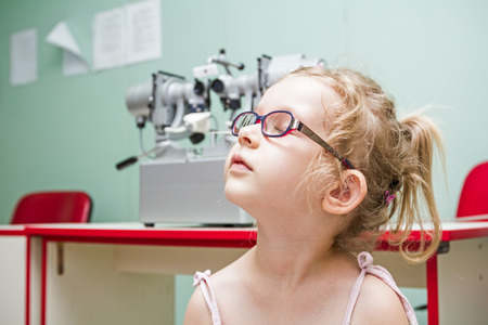 Little girl is at the eye examination showing directions of signs on board.の写真素材