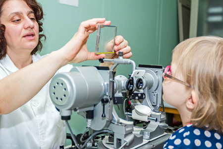 Girl undergoing eye is at examination in clinic with special equipment.の写真素材